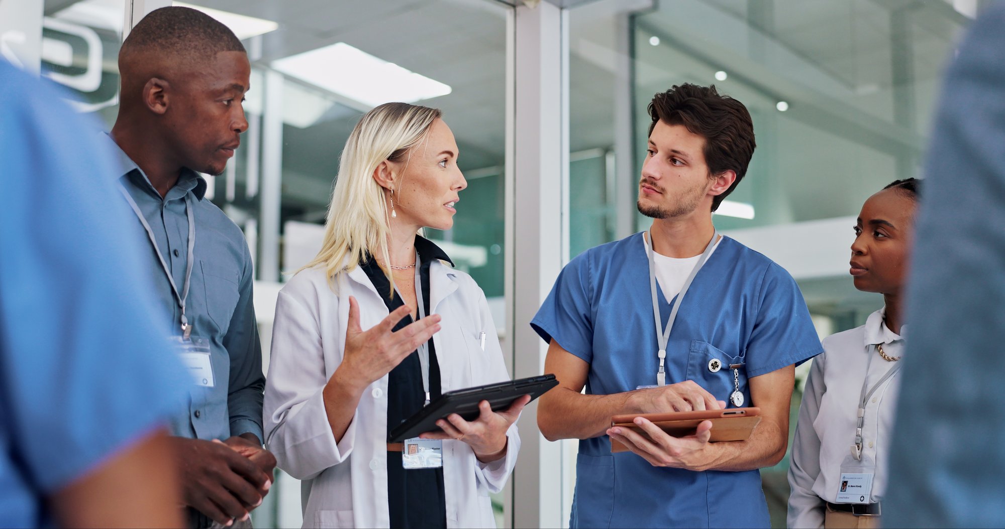 Medical professional talking with colleagues while holding a tablet
