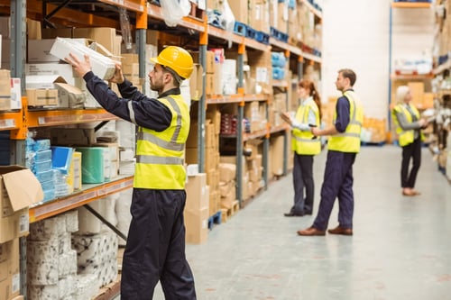Warehouse worker taking package in the shelf in a large warehouse in a hot warehouse