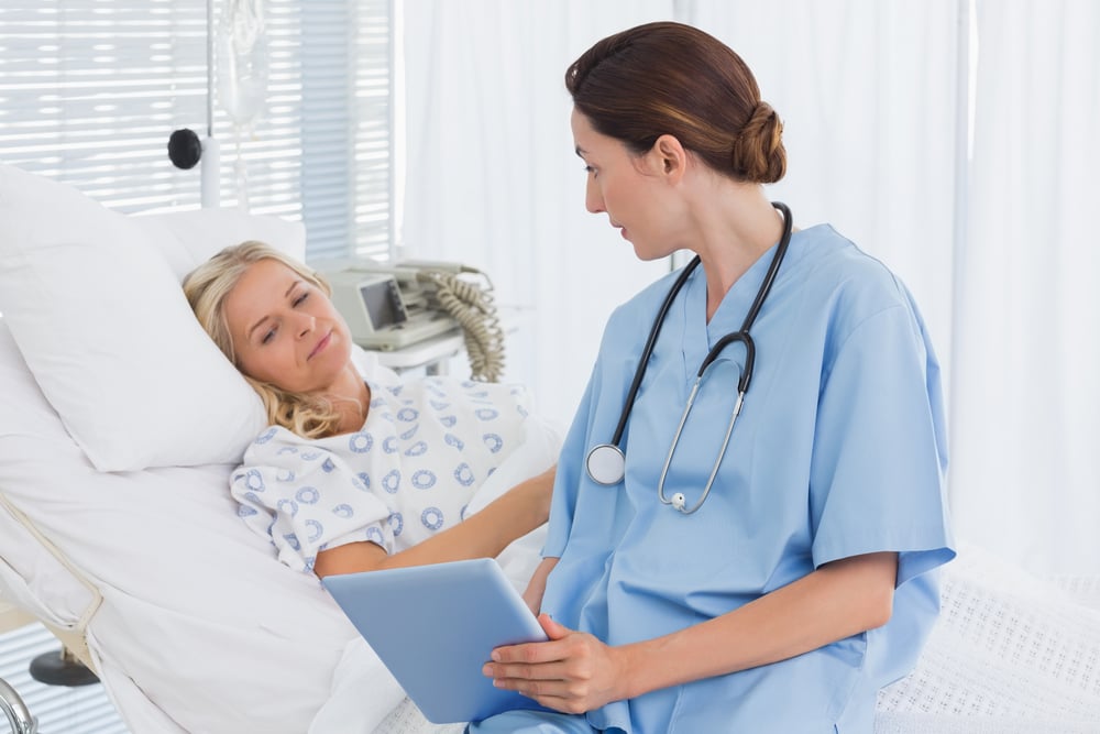 Doctor showing tablet to her patient in hospital room-1